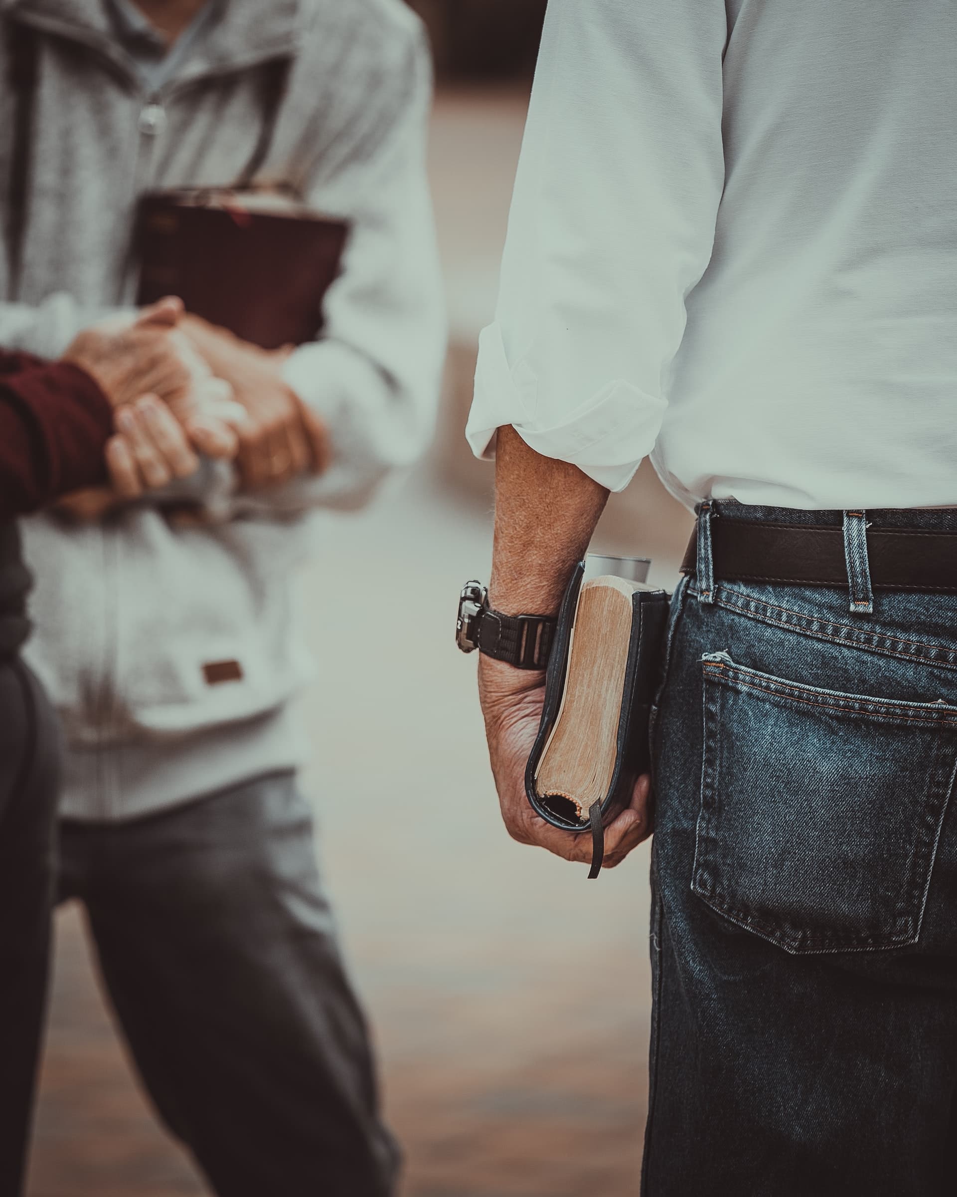 Two believers shaking hands, one holding an open Bible